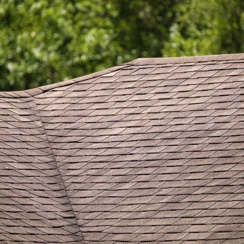 Closeup of house roof top covered with asphalt or bitumen shingles. Waterproofing of new building.