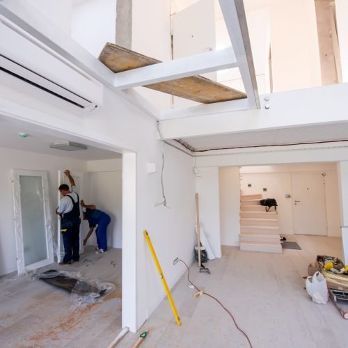 male workers carpenters installing interior glass door with a wooden frame at new luxury apartment