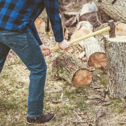 A man cutting wood with an ax during the daytime